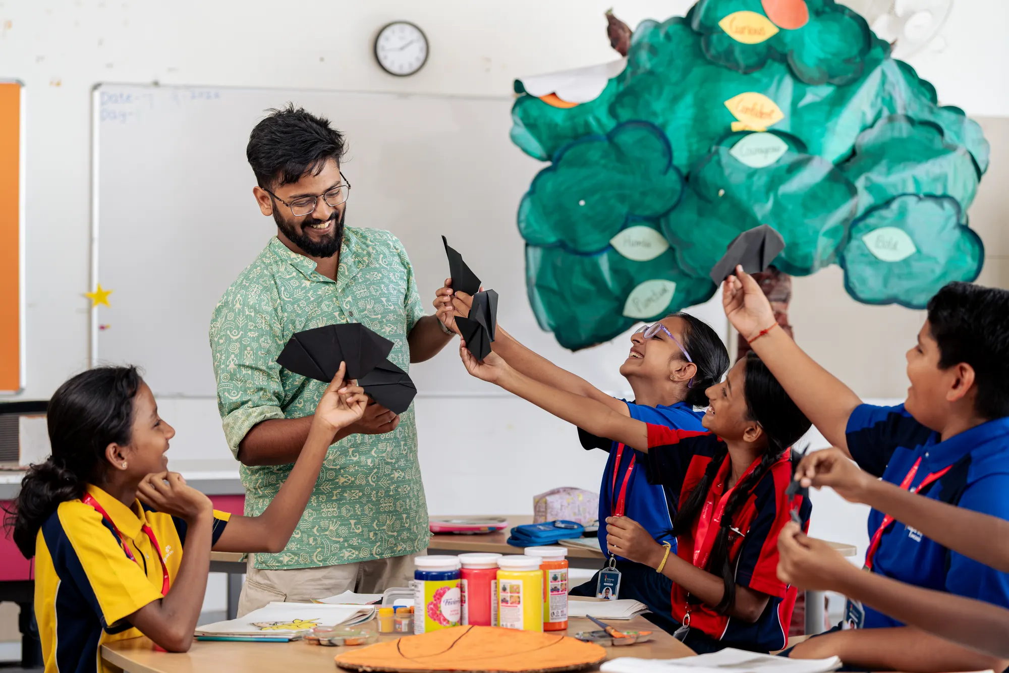 A teacher and Wellsprings students holding paper shapes in the art room