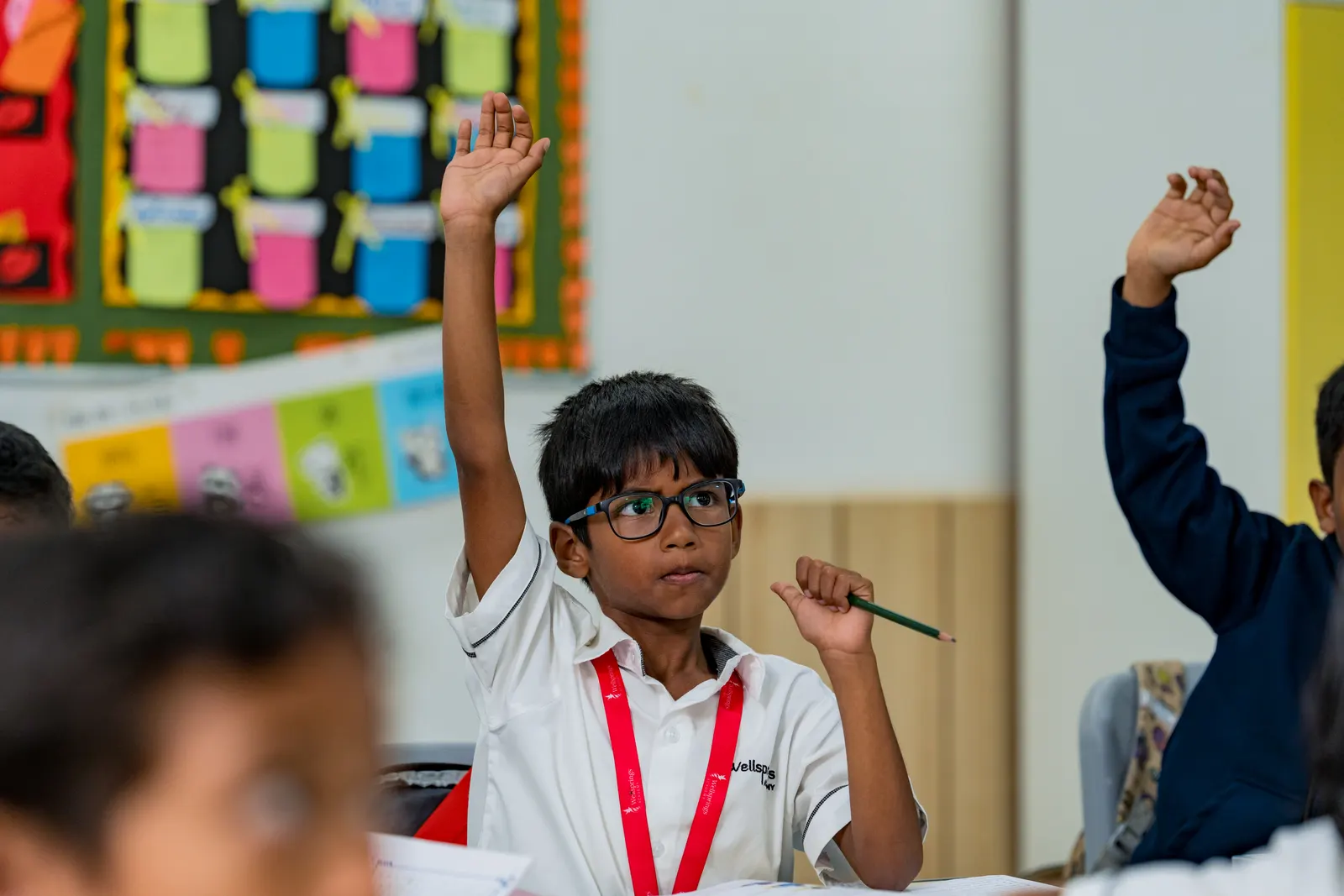 A Wellsprings student raising his hand in class