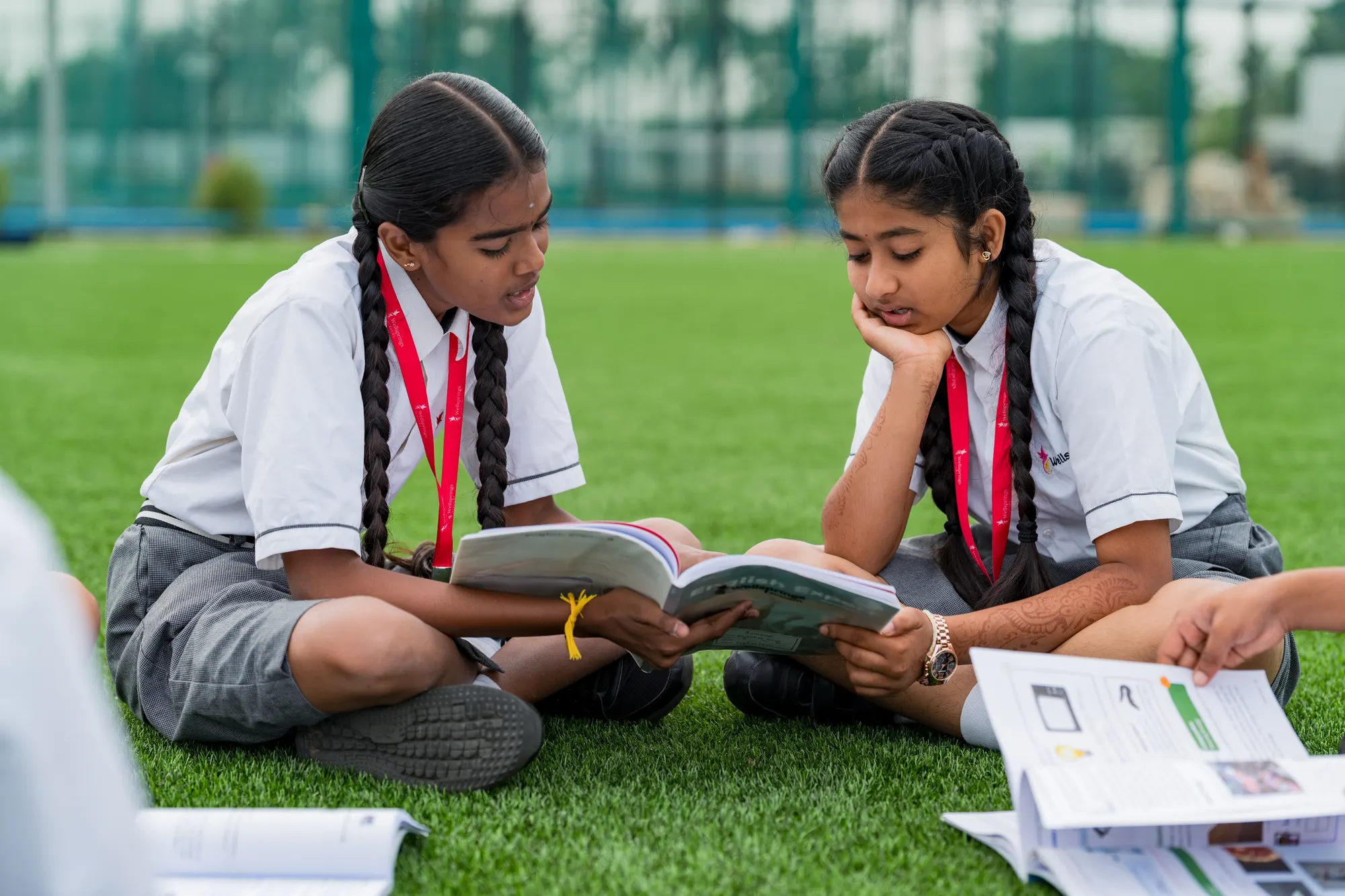 Two Wellsprings students reading a book together on the field
