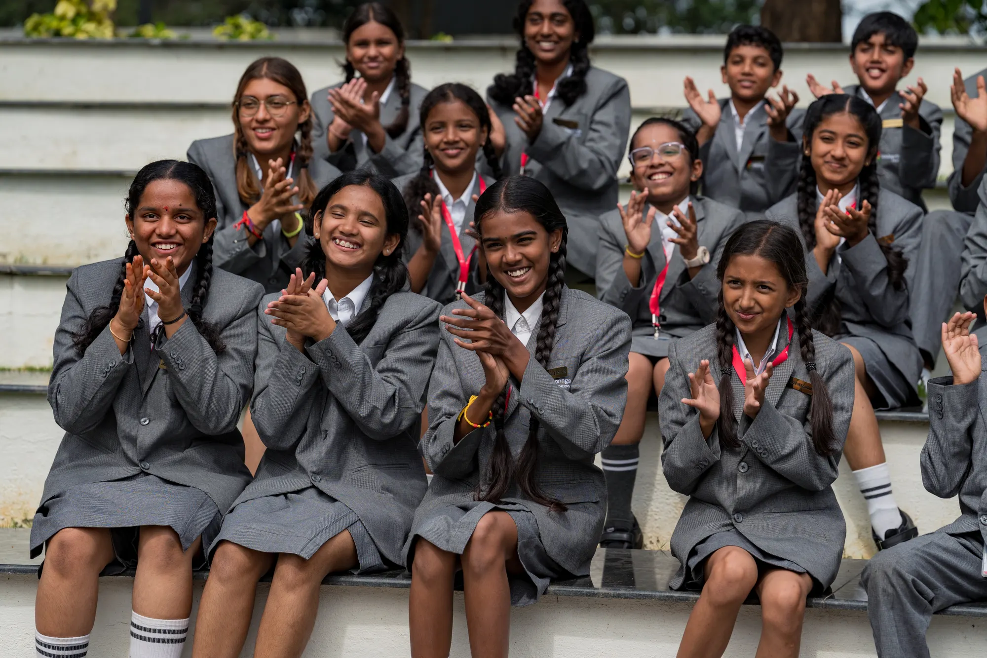 Wellsprings students in grey blazers clapping together on the steps